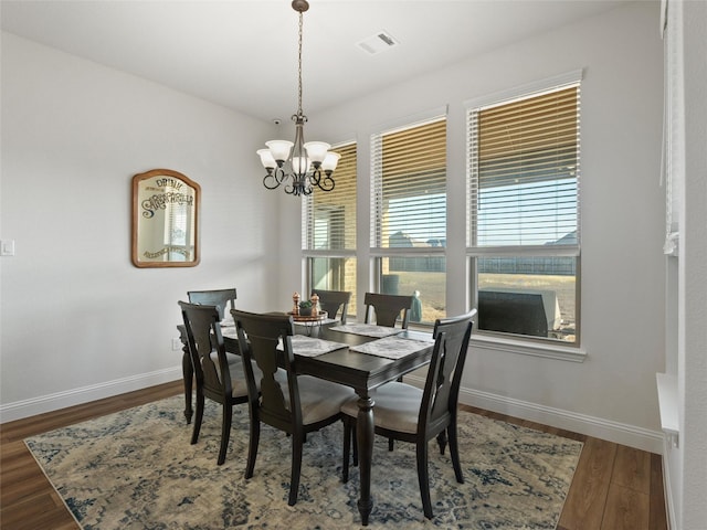 dining room with baseboards, visible vents, a chandelier, and wood finished floors