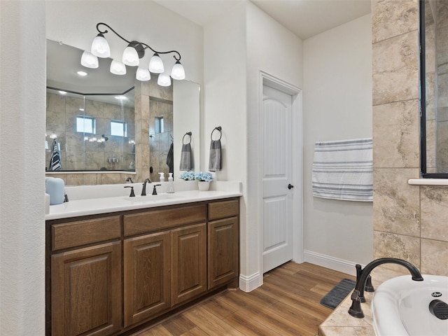 bathroom featuring baseboards, wood finished floors, a bathtub, a tile shower, and vanity