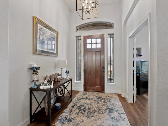 foyer entrance featuring a notable chandelier, baseboards, and wood finished floors