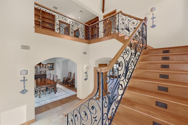 entryway featuring stairs, a high ceiling, visible vents, and arched walkways