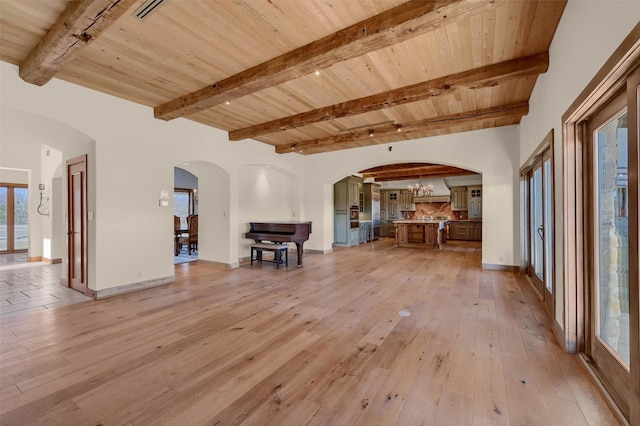 unfurnished living room featuring arched walkways, light wood-style floors, wood ceiling, a chandelier, and beamed ceiling