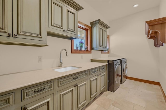 washroom with cabinet space, stone tile floors, baseboards, washer and clothes dryer, and a sink