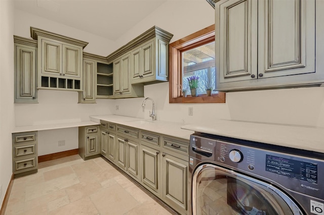 washroom with cabinet space, stone tile floors, baseboards, washer / clothes dryer, and a sink