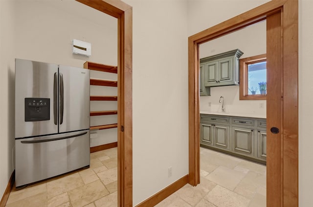 corridor featuring stone tile flooring, a sink, and baseboards