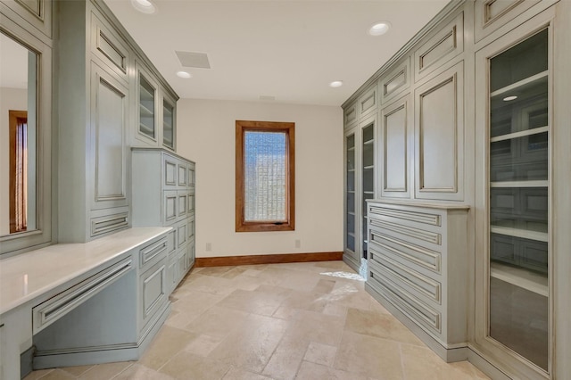 interior space featuring baseboards, visible vents, glass insert cabinets, light countertops, and recessed lighting