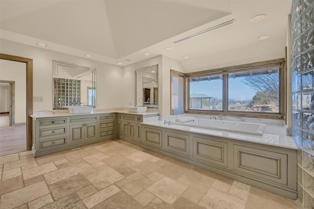 bathroom featuring recessed lighting, stone tile floors, a high ceiling, vanity, and a bath