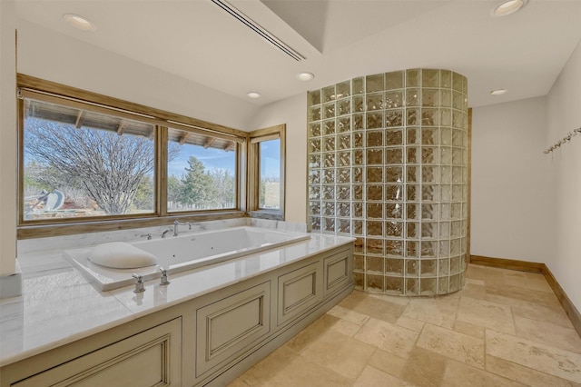 full bath with recessed lighting, stone tile floors, baseboards, and a bath