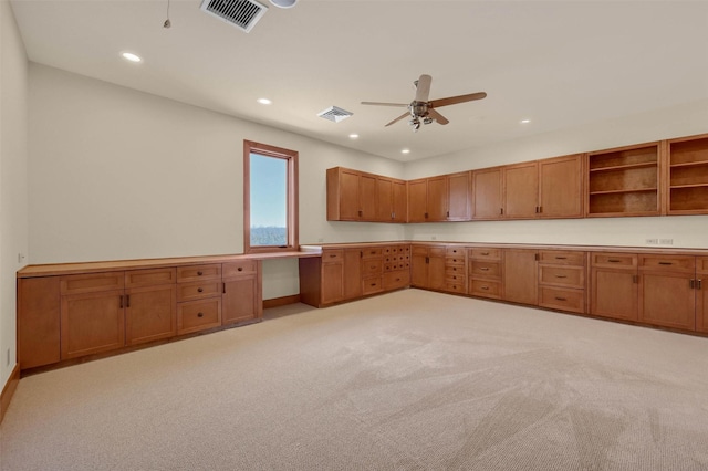 kitchen with visible vents, brown cabinetry, light countertops, open shelves, and built in desk