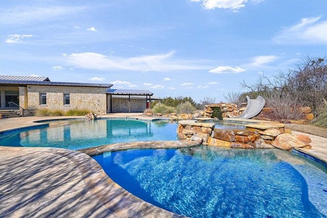 view of swimming pool featuring a water slide, a patio area, and a pool with connected hot tub