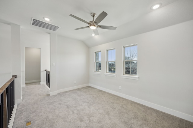 spare room featuring light carpet, baseboards, visible vents, and lofted ceiling