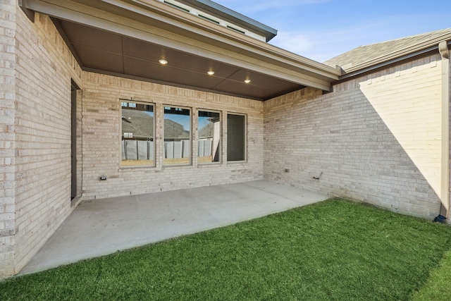 entrance to property featuring a patio and brick siding