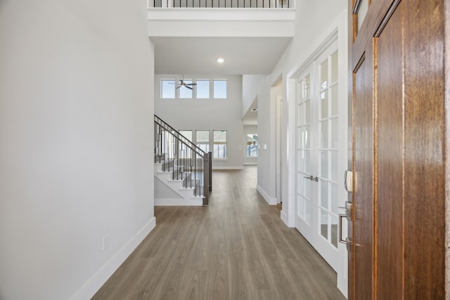 foyer entrance with stairs, a high ceiling, wood finished floors, and baseboards