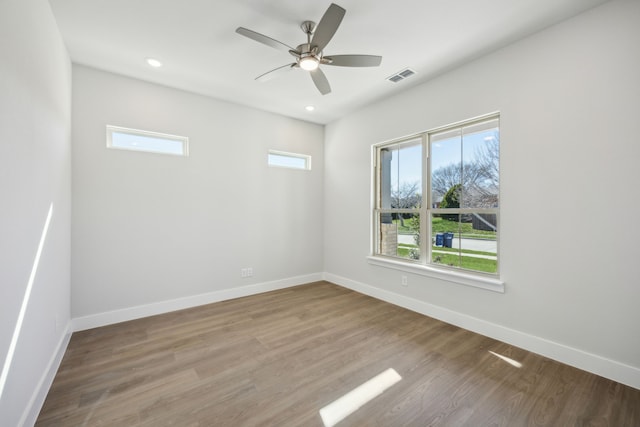 unfurnished room with ceiling fan, wood finished floors, visible vents, and baseboards