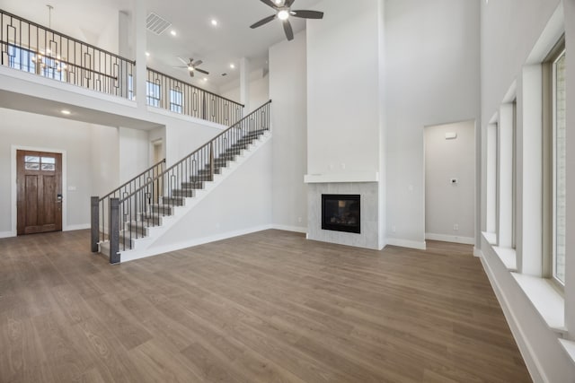 unfurnished living room with baseboards, visible vents, stairway, wood finished floors, and a fireplace