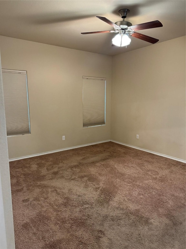 empty room with carpet flooring, a ceiling fan, and baseboards