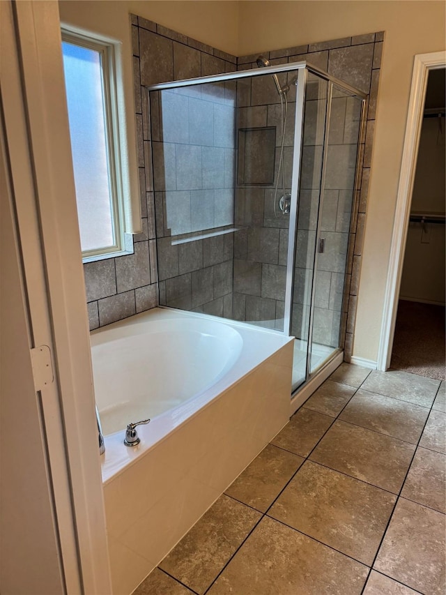 bathroom with a garden tub, a stall shower, a walk in closet, and tile patterned floors