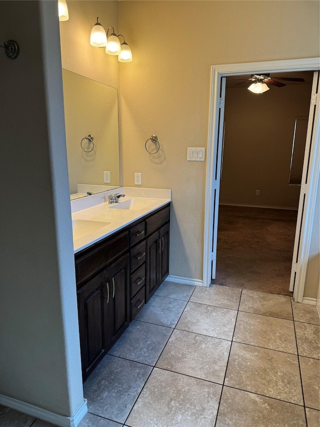 full bath featuring double vanity, a ceiling fan, a sink, tile patterned flooring, and baseboards