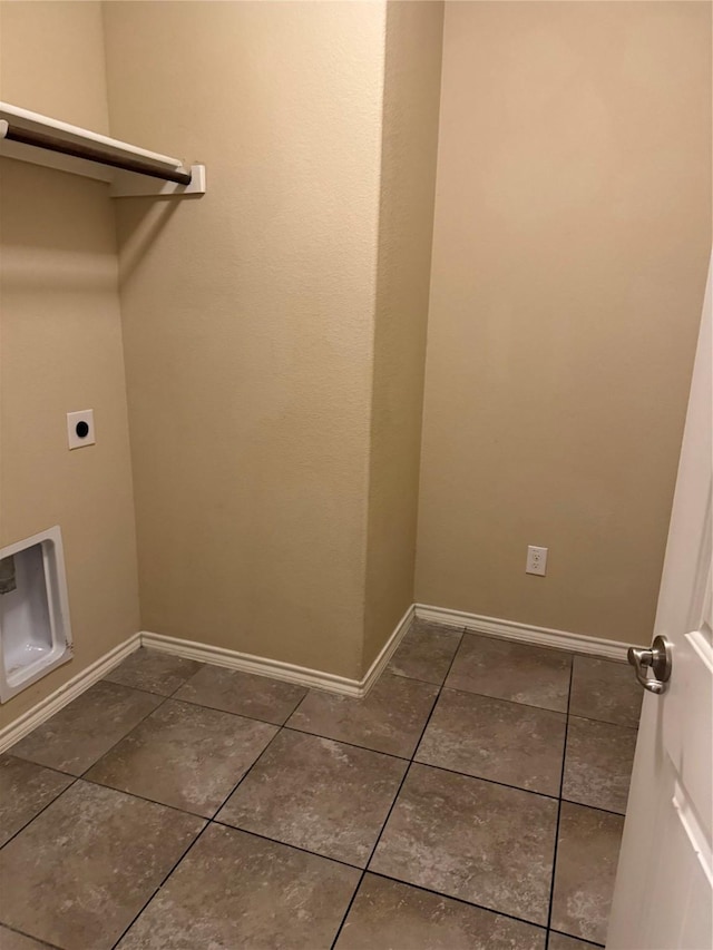 laundry area with heating unit, hookup for an electric dryer, dark tile patterned flooring, laundry area, and baseboards