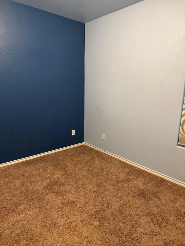 spare room featuring carpet flooring and baseboards