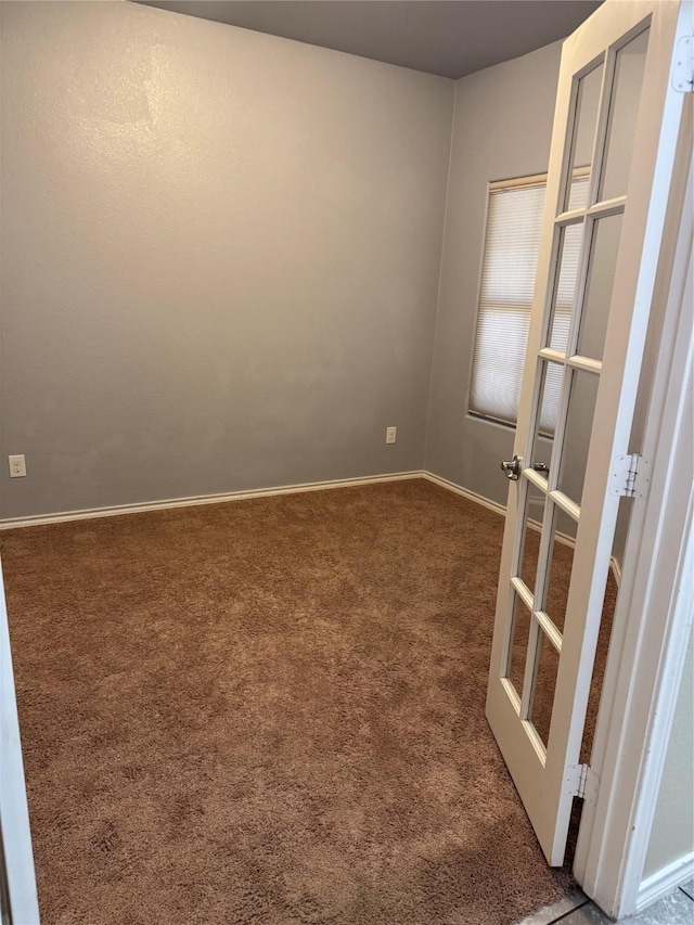 carpeted empty room featuring french doors and baseboards