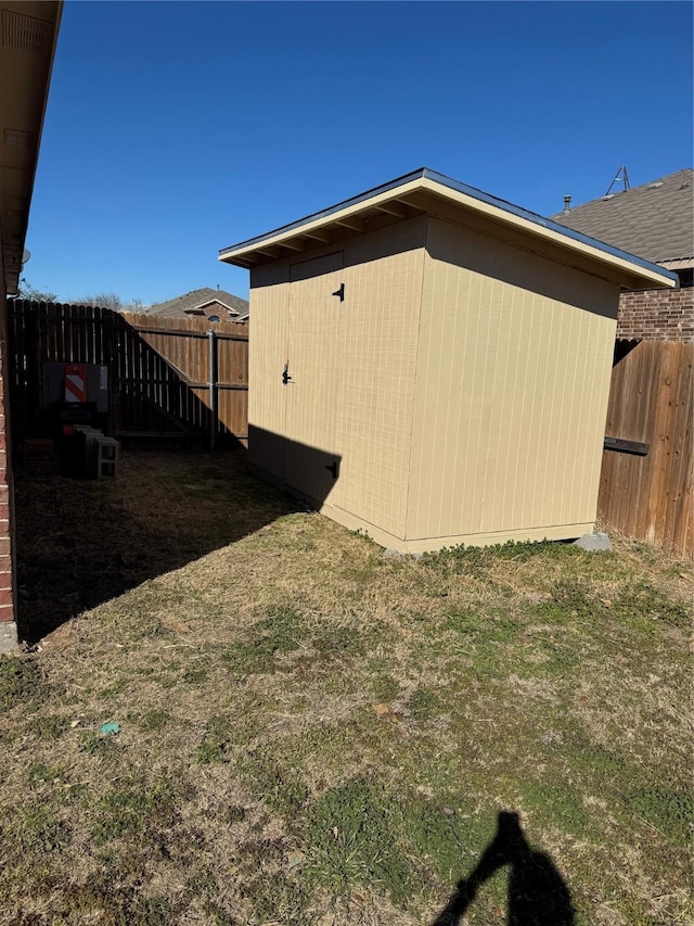 view of home's exterior with an outbuilding, a storage shed, a lawn, and a fenced backyard