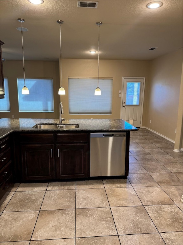 kitchen with dark countertops, a sink, hanging light fixtures, and stainless steel dishwasher