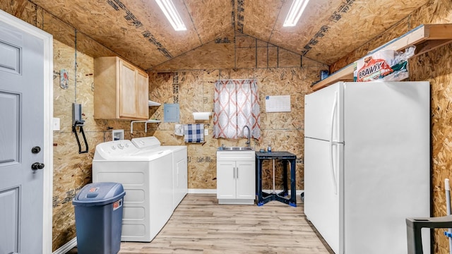 washroom featuring cabinet space, electric panel, light wood-type flooring, separate washer and dryer, and a sink