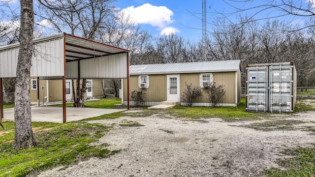 view of front facade with driveway, metal roof, and a detached carport