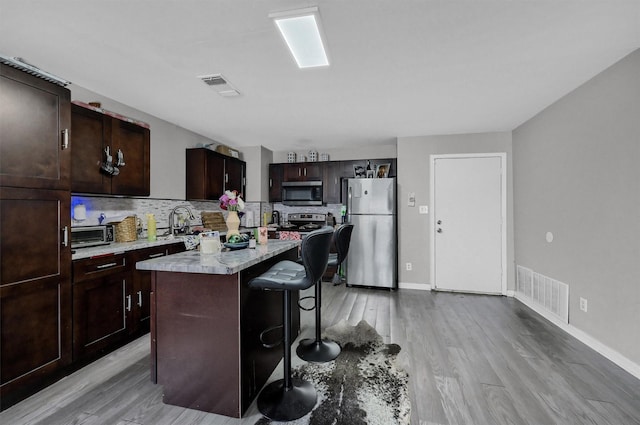 kitchen with appliances with stainless steel finishes, a center island, light countertops, and visible vents