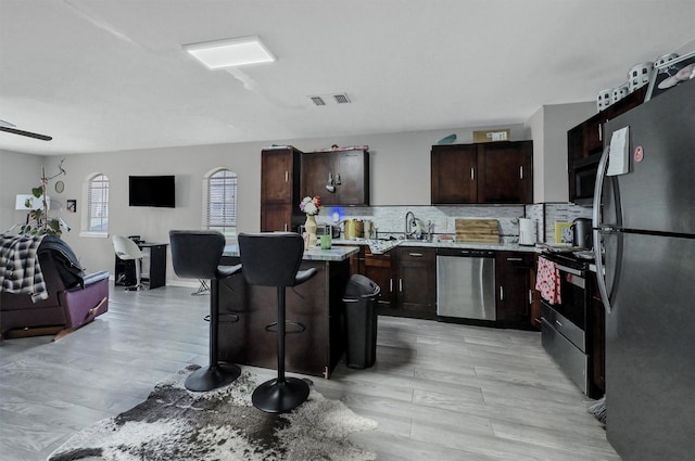 kitchen featuring a breakfast bar area, stainless steel appliances, tasteful backsplash, open floor plan, and a kitchen island