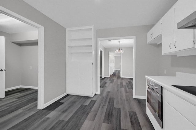 kitchen featuring decorative light fixtures, light countertops, white cabinetry, oven, and wall chimney exhaust hood