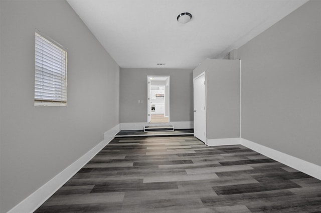 unfurnished room with dark wood-style floors and baseboards