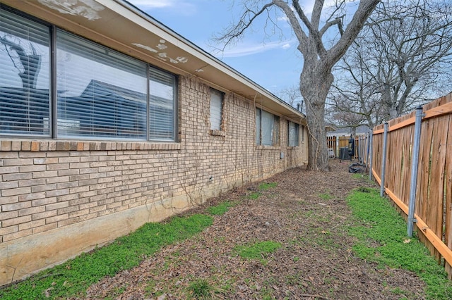 view of side of property with brick siding and a fenced backyard