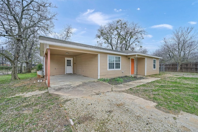 ranch-style house featuring driveway, fence, a carport, and a front yard