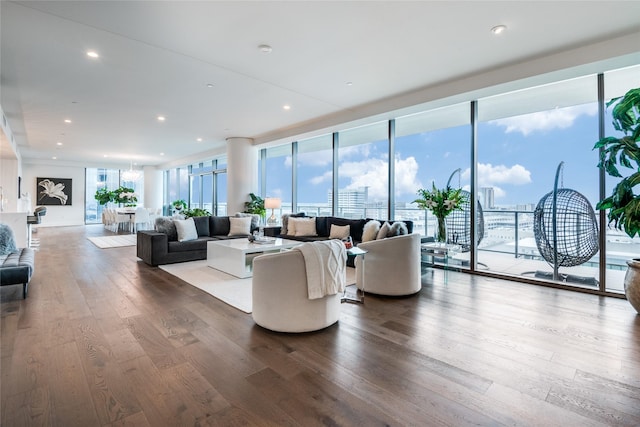 living room with a healthy amount of sunlight, a view of city, floor to ceiling windows, and wood finished floors