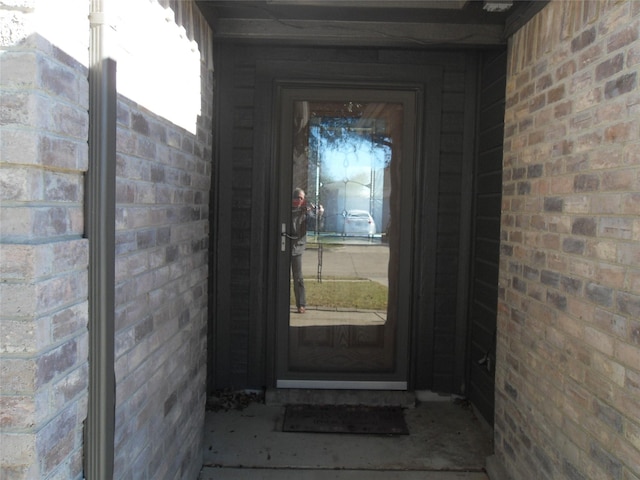 view of exterior entry featuring brick siding