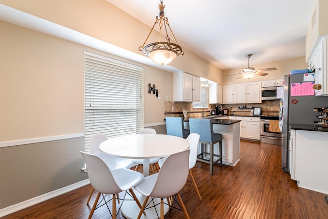 dining room with ceiling fan, dark wood finished floors, and baseboards