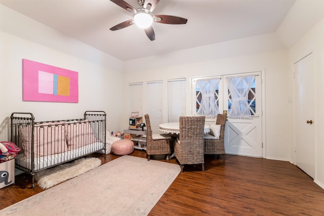 bedroom featuring dark wood-style floors, ceiling fan, baseboards, and a nursery area