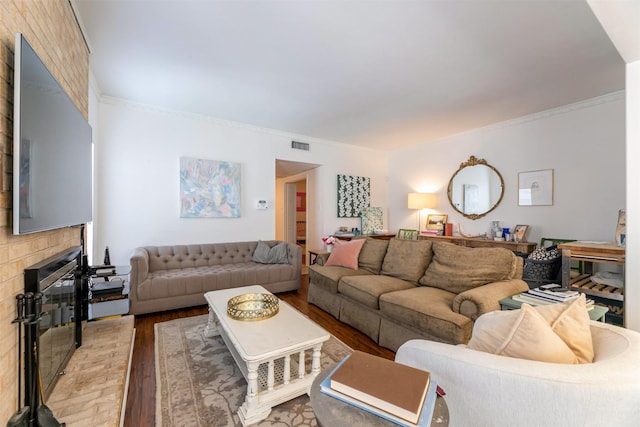 living room with ornamental molding, a brick fireplace, visible vents, and light wood-style floors