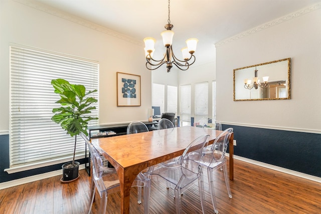 dining room with baseboards, ornamental molding, wood finished floors, and a notable chandelier