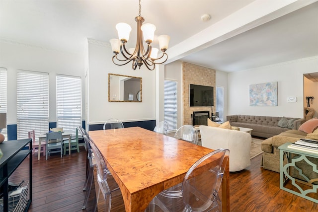 dining space featuring dark wood-style flooring, a brick fireplace, beam ceiling, and a notable chandelier