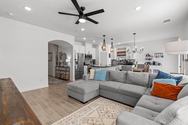 living room with light wood-type flooring, visible vents, arched walkways, and recessed lighting