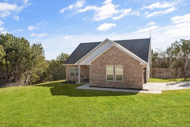 back of property featuring a yard, brick siding, board and batten siding, and fence