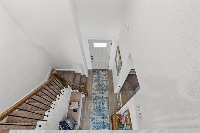 foyer entrance featuring baseboards, a high ceiling, and stairway