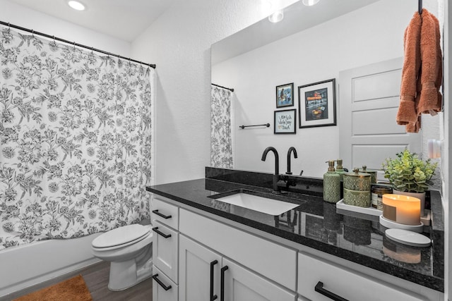 full bathroom with a textured wall, toilet, shower / tub combo, wood finished floors, and vanity