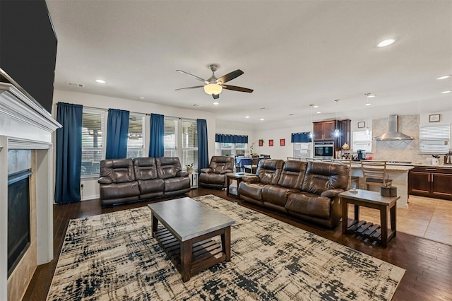 living room with dark wood-style floors, a tiled fireplace, visible vents, and recessed lighting