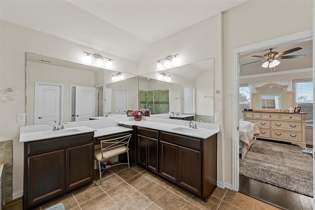 ensuite bathroom with vaulted ceiling, connected bathroom, vanity, and tile patterned floors