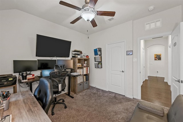 carpeted home office featuring lofted ceiling, ceiling fan, visible vents, and baseboards