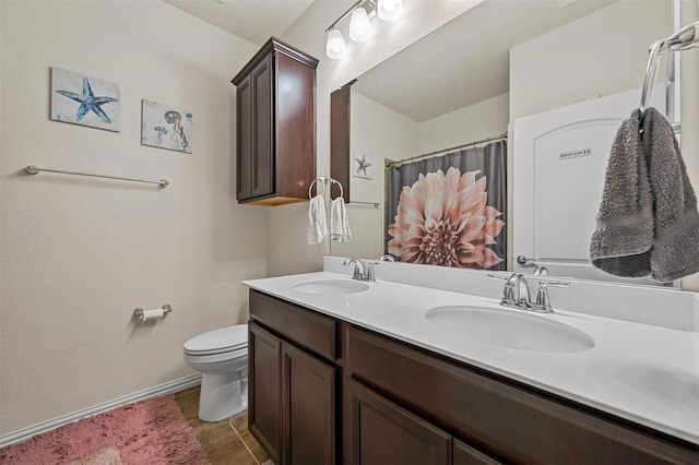 bathroom with double vanity, a sink, toilet, and baseboards