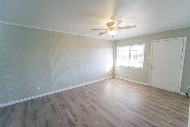 empty room with crown molding, baseboards, light wood-style flooring, and a ceiling fan